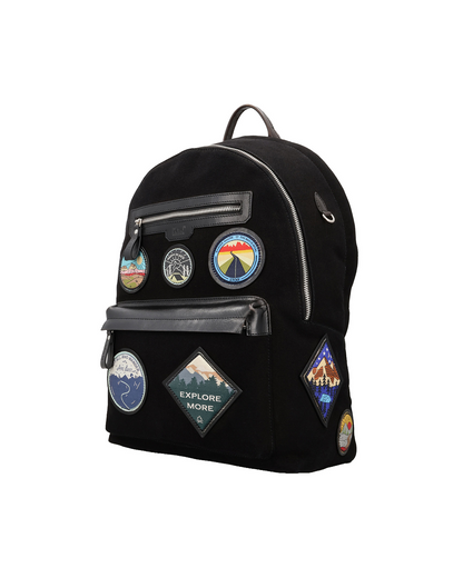 ek inch Black canvas and reclaimed leather backpack with travel-inspired embroidered leather patches, two zip pockets for a passport, iPad, earphones, and small accessories.