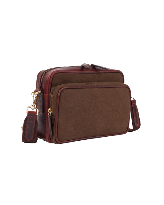 Angled front view of the Studio Ek Inch Metropolitan Sling bag in brown waterproof canvas and reclaimed leather, featuring a spacious front zip compartment, adjustable shoulder strap and antique brass hardware. Designed as a premium crossbody bag for travel and everyday use, it combines practical storage with timeless craftsmanship.