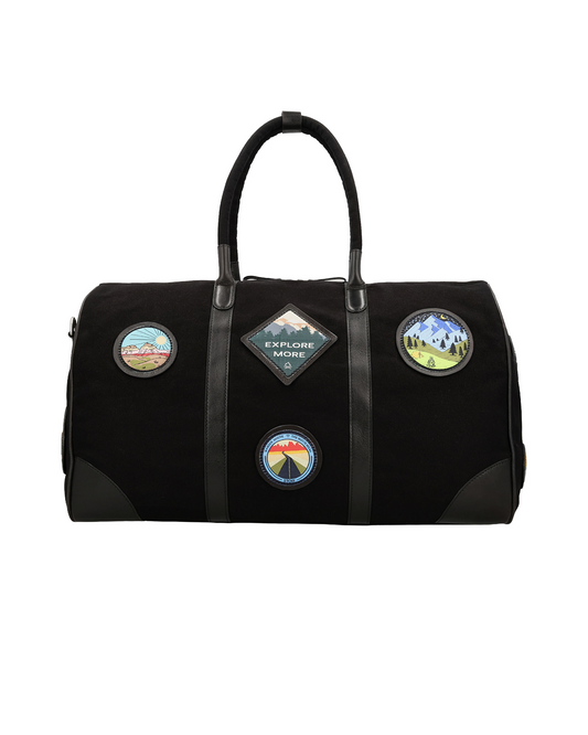 Front view of the Studio Ek Inch Kasol weekender duffle bag in black canvas and reclaimed leather, featuring handcrafted travel-inspired patches and spacious interiors. This premium canvas and leather hold all bag is designed for weekend getaways, airport travel and overnight trips by one of India's premium bag brands.