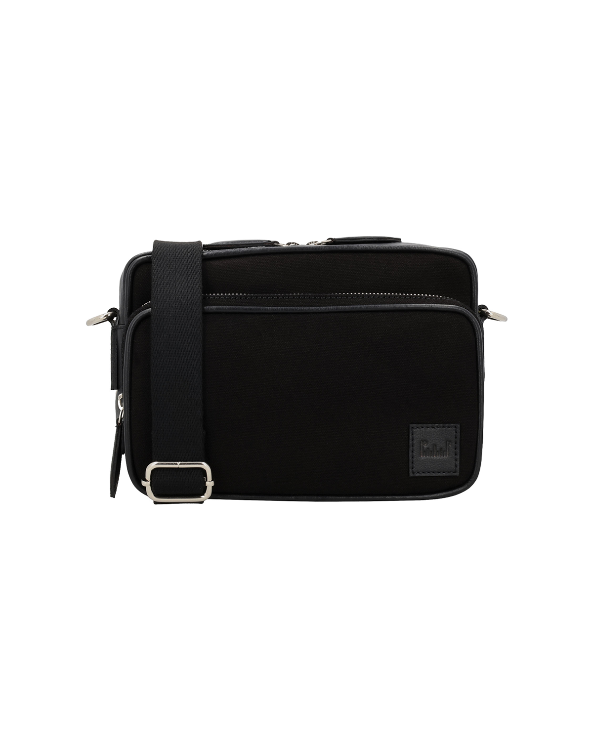 Front view of the Studio Ek Inch Metropolitan crossbody bag in black waterproof canvas and reclaimed leather, featuring a spacious front zip pocket, adjustable shoulder strap and premium metal hardware. Designed as a premium crossbody bag for men, it offers organized storage for travel and everyday essentials.