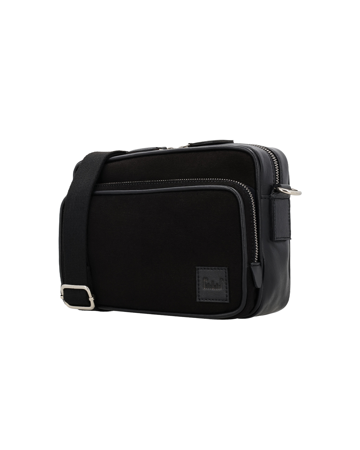 Angled front view of the Studio Ek Inch Metropolitan sling bag in black canvas and reclaimed leather with spacious zip compartments and premium hardware. A handcrafted crossbody bag for men designed for work, travel and everyday journeys.