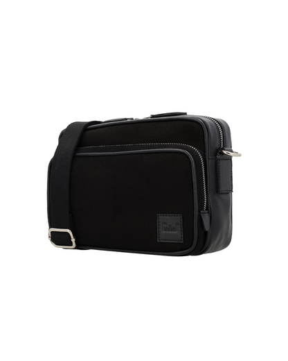 Angled front view of the Studio Ek Inch Metropolitan sling bag in black canvas and reclaimed leather with spacious zip compartments and premium hardware. A handcrafted crossbody bag for men designed for work, travel and everyday journeys.