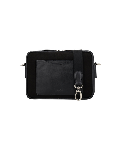 Back view of the Studio Ek Inch Metropolitan sling bag in black waterproof canvas and reclaimed leather, featuring a rear slip pocket and detachable shoulder strap. A premium crossbody bag designed for travel and everyday carry.