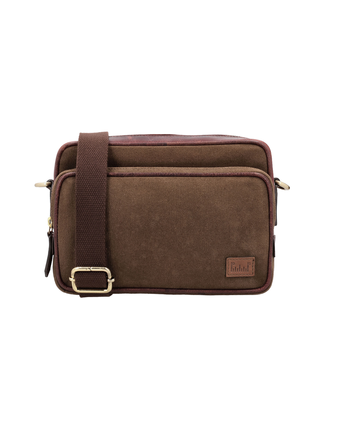 Angled front view of the Studio Ek Inch Metropolitan Sling bag in brown waterproof canvas and reclaimed leather, featuring a spacious front zip compartment, adjustable shoulder strap and antique brass hardware. Designed as a premium crossbody bag for travel and everyday use, it combines practical storage with timeless craftsmanship.